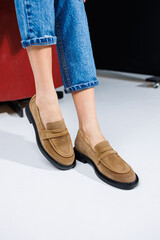Casual women's fashion. Classic shoes for women. Slender female legs in trousers and brown stylish casual loafers. Women's comfortable summer shoes.