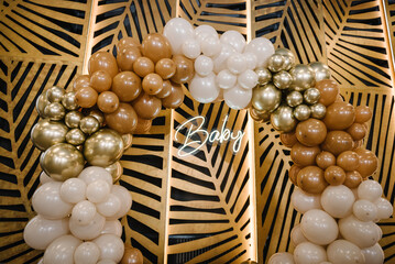 Text baby. Arch decorated with brown, beige and golden balloons. Celebration baptism concept....