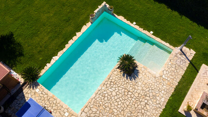 Aerial view of a rectangular pool with stairs to descend and climb into the water. The water is...