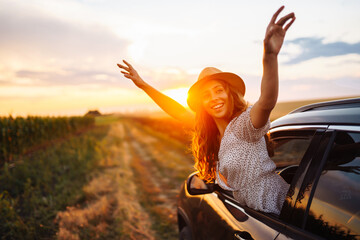Relaxed happy woman on summer road trip travel vacation leaning out car window. Lifestyle, travel,...
