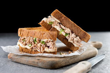 Tuna sandwich with mayo and vegetables on gray stone background.