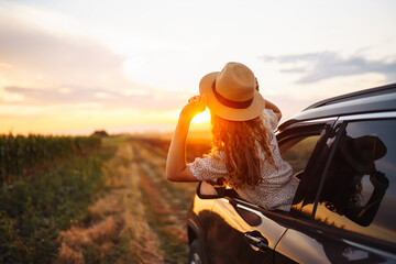 Relaxed happy woman on summer road trip travel vacation leaning out car window. Lifestyle, travel,...