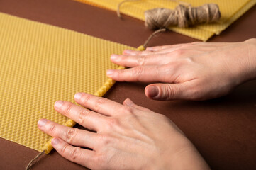 Beeswax honeycomb candle sheets and jute thread on brown background. Making candle step by step,...