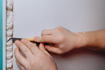 A man's hand holds a stationery knife in his hand and makes a wall putty with clay. Making repairs...