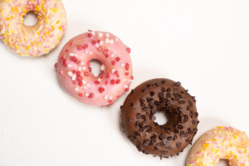 Four donuts in a row - white, pink and chocolate on a white background top view