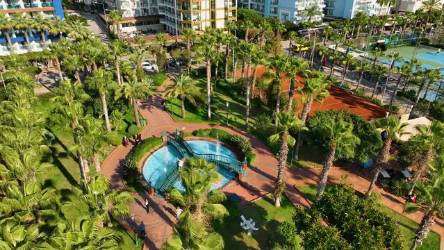 A park and a large recreation area playgrounds basketball and tennis courts fountains palm trees a beautiful beach