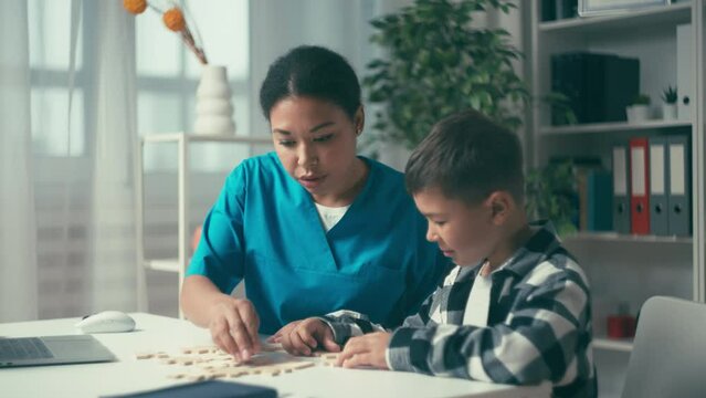 Female doctor and boy putting puzzle together, child development assessment