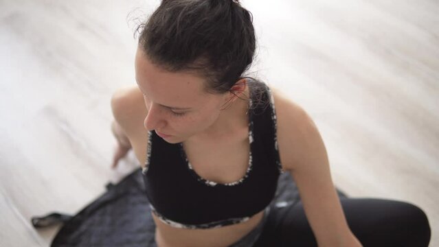Young relaxed happy woman wearing sportswear and practicing yoga, doing revolved exercise, Parivrtta Sukhasana pose black at home