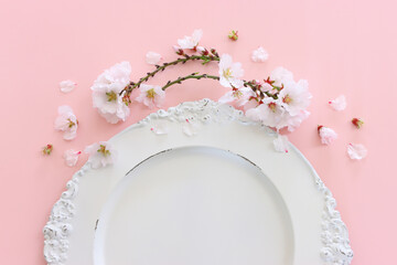 Top view of vintage white empty plate over spring cherry tree flowers. Flat lay