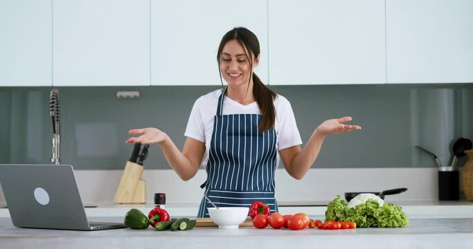 Blogger chef makes food blog about cooking salad woman in an apron at home in kitchen tells the recipe on camera in her food blog Online broadcast, woman leads food blog or course about cooking