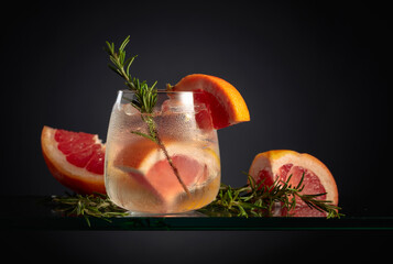 Cocktail gin tonic with ice, grapefruit, and rosemary.