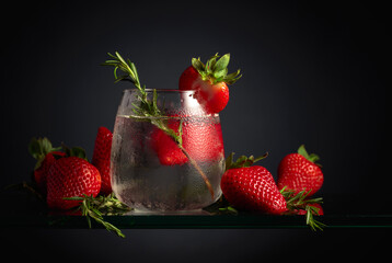 Cocktail gin tonic with ice, strawberries, and rosemary.