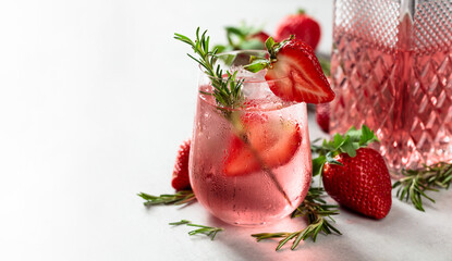 Gin and tonic cocktail with natural ice, strawberries, and rosemary.