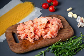 Raw chopped salmon and spaghetti for cooking on a gray background. A set of fish and vegetable ingredients for cooking.