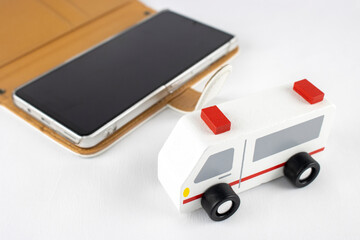 スマートフォンと玩具の救急車。連絡するイメージ