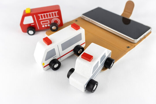 スマートフォンと玩具のパトカー、消防車、救急車。連絡するイメージ