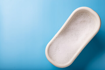 Toy bath with soap suds on a blue background. The concept of cleanliness, hygiene.