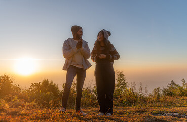 Man and woman tourists in the mountains at sunset. Happy couple in love.