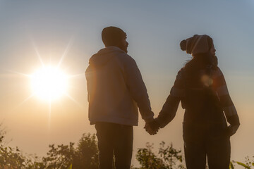 Fototapeta premium Close-up shot of a couple holding hands while walking watching the sunrise.