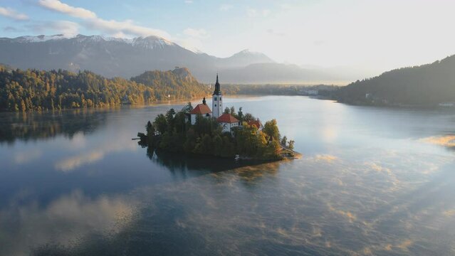 Elevated view of a colourful sunrise at Lake Bled with the Pilgrimage Church of the Assumption of Maria on a small island and snowcapped Mountain Julian Alps in the background, Slovenia