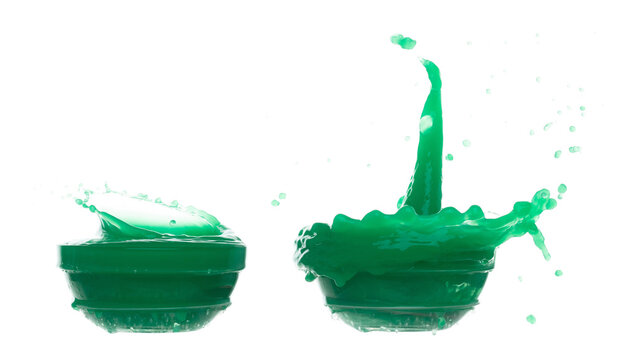 Green paint liquid fly in mid air, spill out glass bowl, apple vegetable juice falling scatter, explosion float in shape form droplet line. White background isolated freeze motion high speed shutter