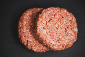 raw beef cutlet for cooking burger on a dark background