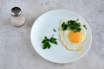 A healthy breakfast with a fried egg and chopped parsley isolated on marble background