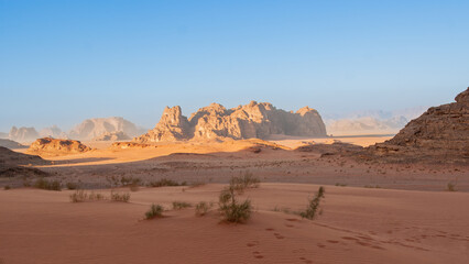 Fototapeta na wymiar Bizarre shapes of rocks in deserted desert. Jordan. Desert of Wadi Rum. Landscape is similar to Martian landscapes. Sand is of beautiful pink color in rays of setting sun. Nature concept for design