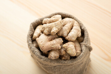Ginger root in small bag against wooden table. Ginger roots close up