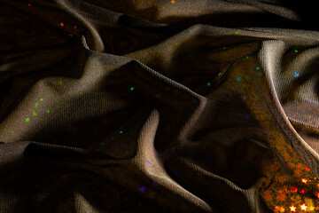 Magic, fairy tale dark background of black tulle fabric and holographic foil with colorful stars....