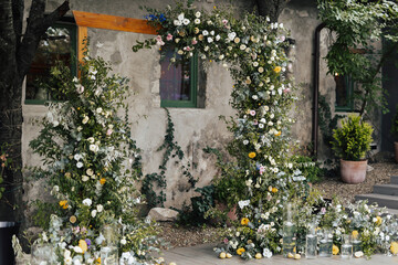 Fototapeta na wymiar Place for wedding ceremony with wedding arch decorated with flowers, greenery and lemons. Tuscany style.