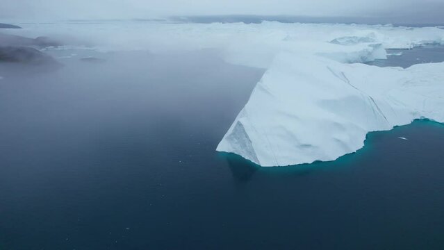 Elevated view flying between the iceberg peaks and large icebergs floating shrouded in fog at Ilulissat Icefjord, Arctic Ocean, Greenland Ice Sheet, Icecap, Ilulissat, Climate Change