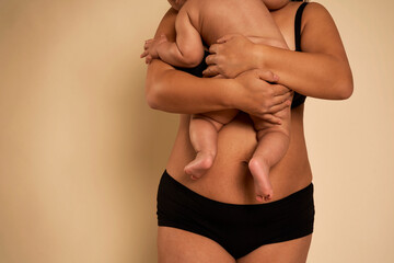 Unrecognizable woman in underwear holding a toddler - obrazy, fototapety, plakaty
