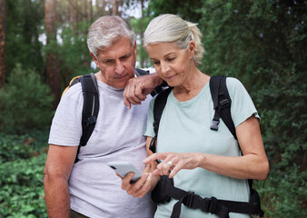 Hiking, forest and elderly couple with phone for gps, location or navigation while exploring together. Online, maps and active senior man with woman checking direction while backpacking in nature