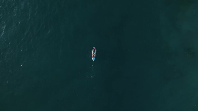 Over under shot of young happy active couple paddling together at sunset in the ocean aerial view
