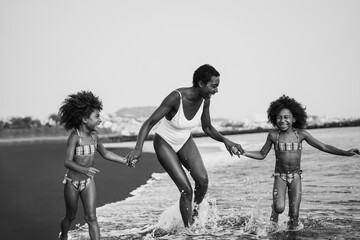 African sisters twins running on the beach with smiling mother - Focus on mom face - Black and...