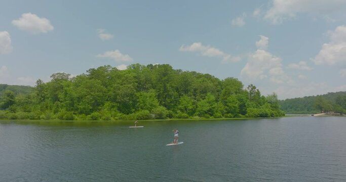 Aerial: Drone Panning Shot Of Women Paddleboarding On Rippled River Under Clouds - Tuscaloosa, Alabama