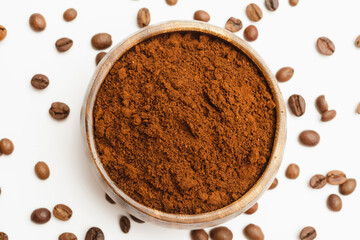 Ground coffee and coffee beans in wooden bowl on white background