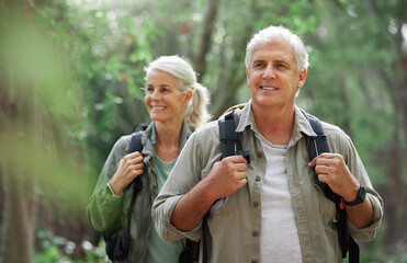 Hiking, elderly couple and active seniors in a forest, happy and relax while walking in nature....