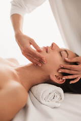 Massage therapist massaging face of client in beauty clinic