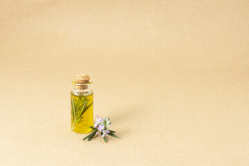 Oil in a bottle and fresh organic rosemary isolated on brown old paper background. Fresh, organic herbs , healthy life, food concept.