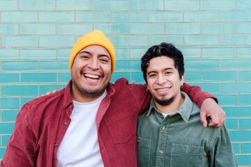 Happy man with brother standing in front of turquoise brick wall