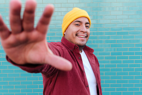 Happy man stop gesturing in front of turquoise brick wall