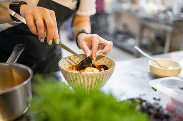 woman chef cooking seafood soup on restaurant kitchen