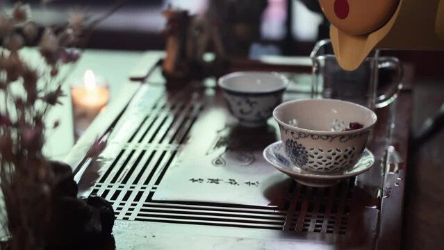 female master pours hot water into bowl with puero petals for a tea ceremony, close-up