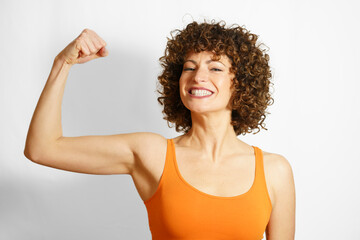 Happy woman flexing muscles against white background