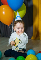Baby boy in a party hat happy to receive a present. First birthday baby boy party.