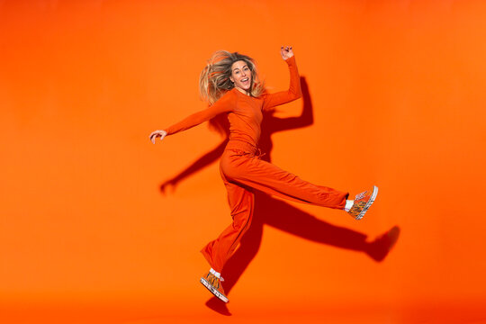 Woman making fake kick pose against orange background