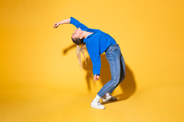 Woman with hand raised dancing against yellow background