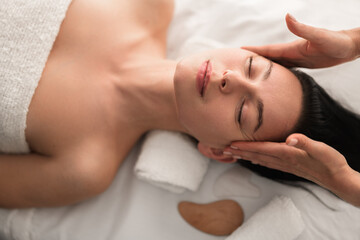 Fototapeta na wymiar Masseuse massaging clients temples in spa salon